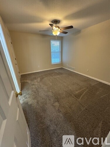 A room with a ceiling fan and a window with blinds.