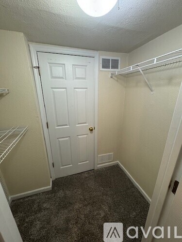 A small bedroom with a white door and a shelf.