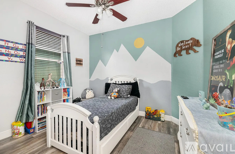 A bedroom with a mountain mural on the wall and a white bed.