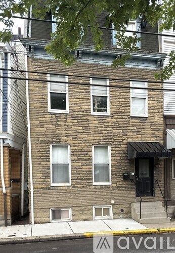 A brick building with a black awning and a sign that says "avail" in front of it.