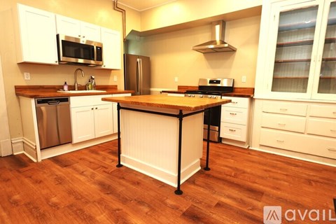 A kitchen with white cabinets and a wooden island.
