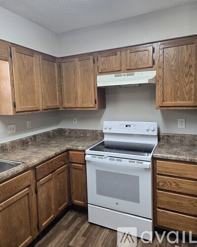 A kitchen with wooden cabinets and a white stove top oven.