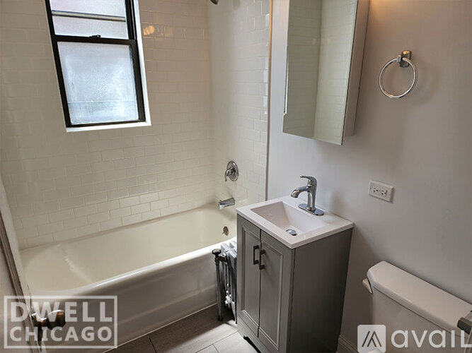 A white bathroom with a tub, sink, and mirror.