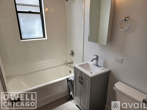 A white bathroom with a tub, sink, and mirror.