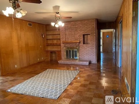 A living room with a brick fireplace and a rug on the floor.