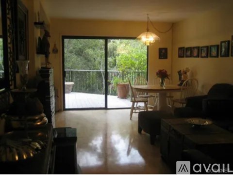 A living room with a black couch and a glass door leading to a balcony.