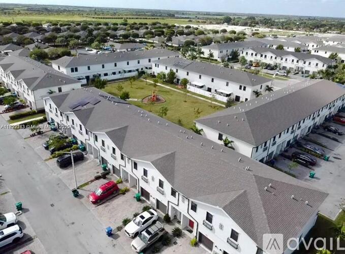A large white building complex with a parking lot in front.