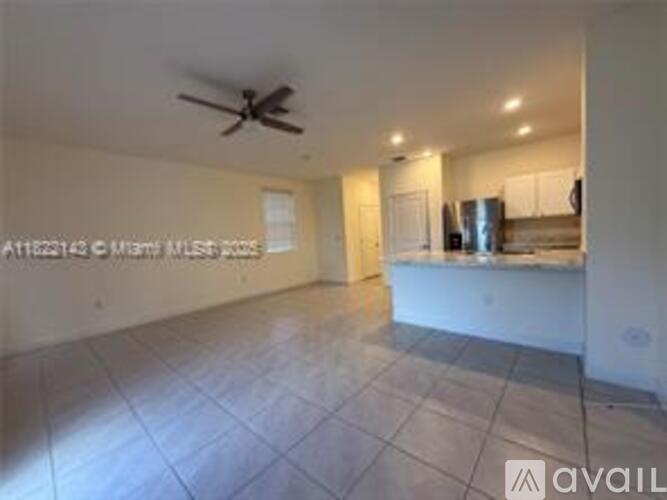 A spacious room with a ceiling fan and tiled floor.