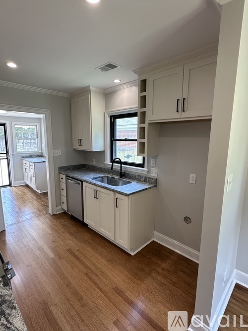 A kitchen with white cabinets and a black countertop.