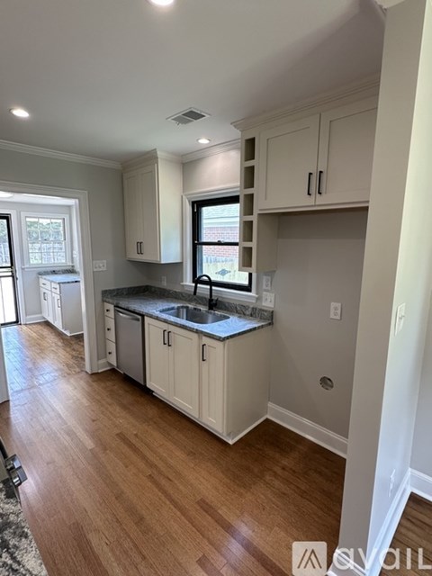 A kitchen with white cabinets and a black countertop.
