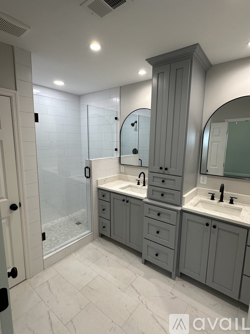 A bathroom with a walk-in shower and double sinks.