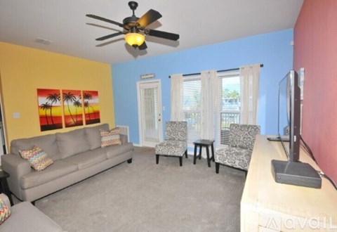 A living room with a grey couch and a ceiling fan.