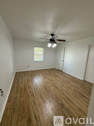 A room with wooden flooring and a ceiling fan.