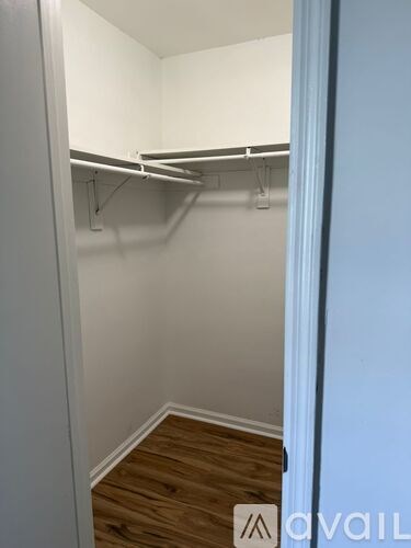 A small, empty room with a wooden floor and white walls.