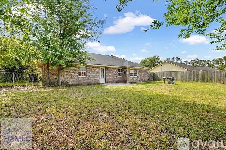 A house with a fenced yard and trees in the background.