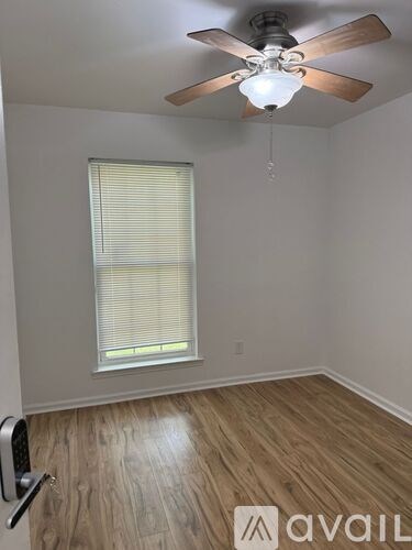 A room with a ceiling fan and a window with blinds.