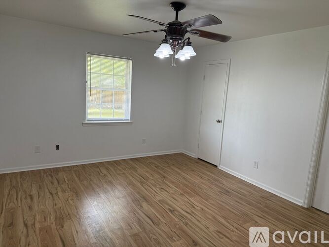 A room with a ceiling fan and a window with blinds.