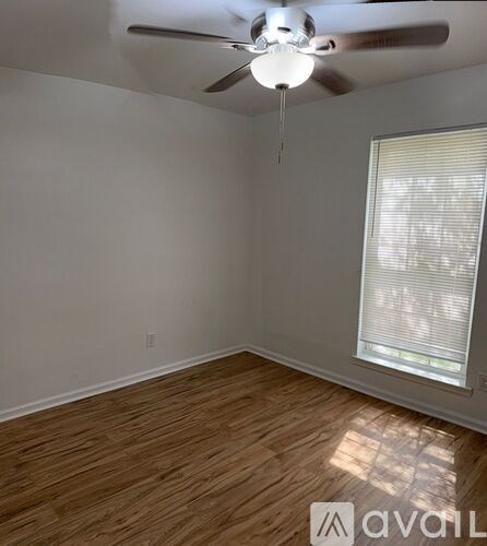 A room with a ceiling fan and a window with blinds.