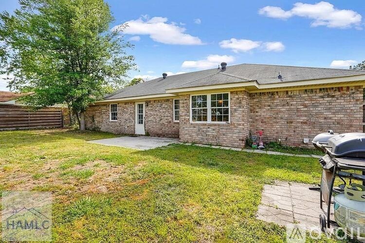 A house with a brick exterior and a white door is surrounded by a grassy area.