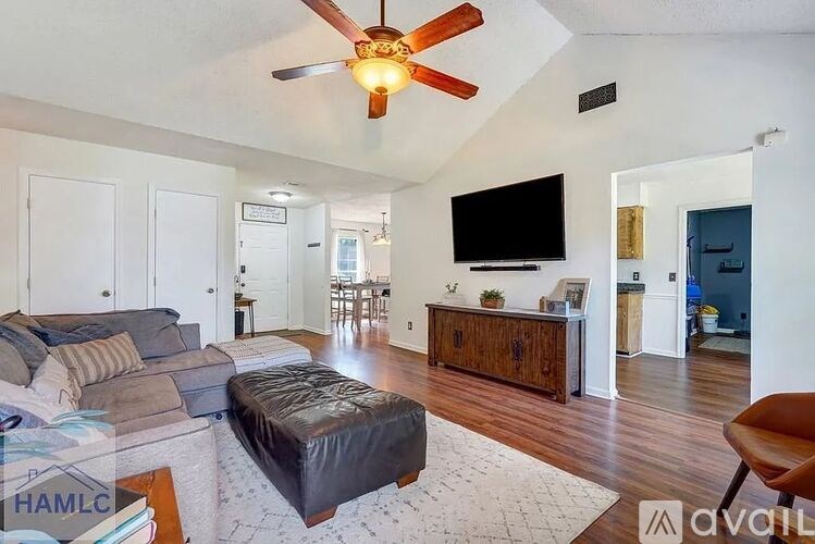 A living room with a ceiling fan and a flat screen TV.