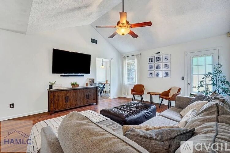 A living room with a couch, a television, and a ceiling fan.