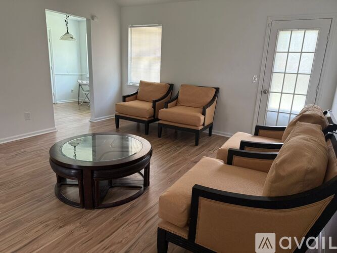 A living room with a glass table and two chairs.