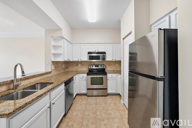 A kitchen with a black refrigerator, sink, and stove.