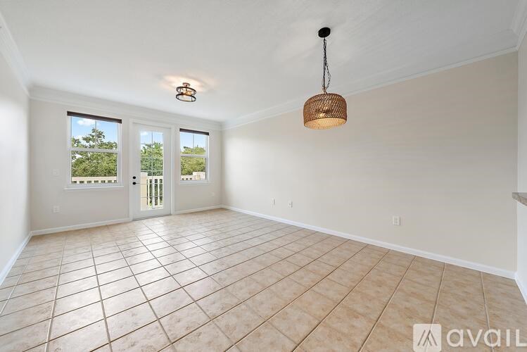 A large empty room with tiled flooring and a hanging light fixture.
