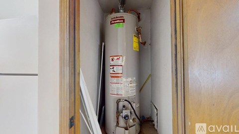 A water heater is installed in a narrow space between a wall and a door.