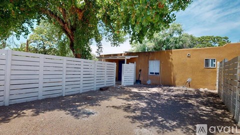A house with a white fence and a brown wall is available for rent.
