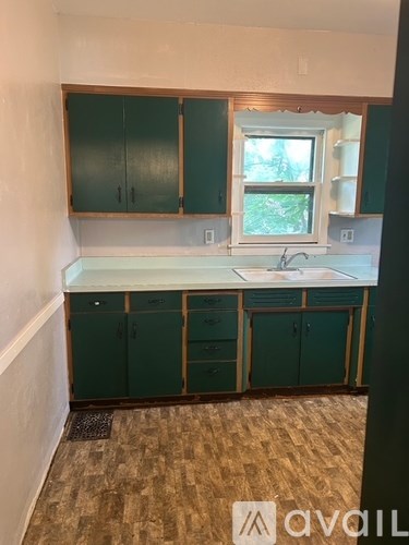 A kitchen with green cabinets and a window.
