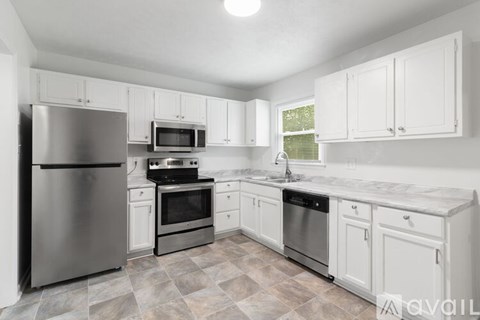 A kitchen with white cabinets and a tiled floor.