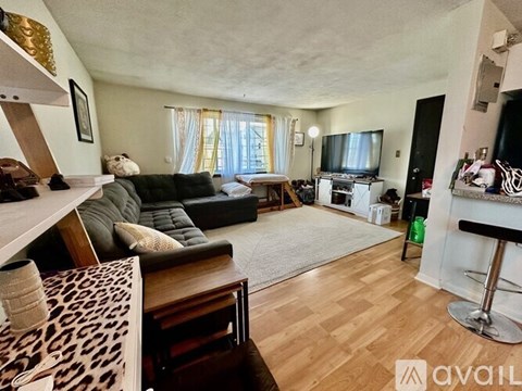A living room with a leopard print couch and a wooden floor.