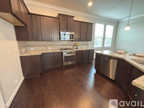 A kitchen with dark brown cabinets and a granite countertop.
