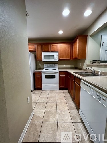 A kitchen with brown cabinets and white appliances.