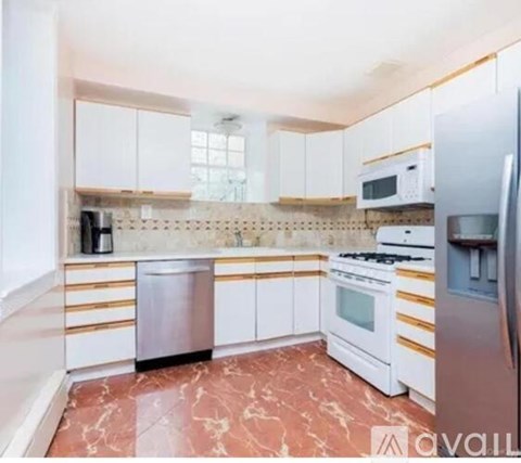 A kitchen with white cabinets and a marble floor.