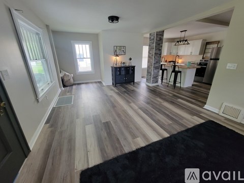 A living room with a black rug on the floor.