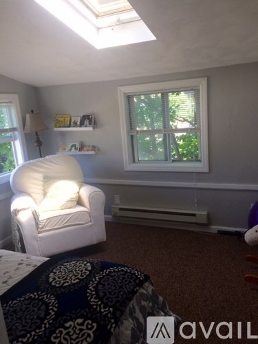 A living room with a white chair and a window.