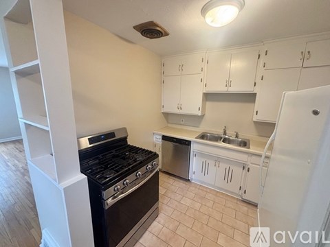 A kitchen with a black stove top oven and white cabinets.
