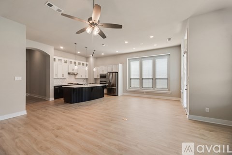 A spacious living room with a ceiling fan and lighting fixtures.