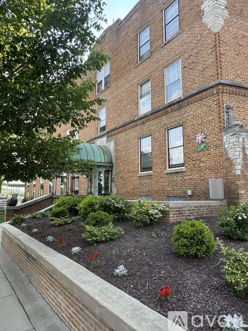 A brick building with a green awning and a flower on the wall.