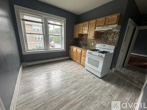A kitchen with a white stove top oven and wooden cabinets.