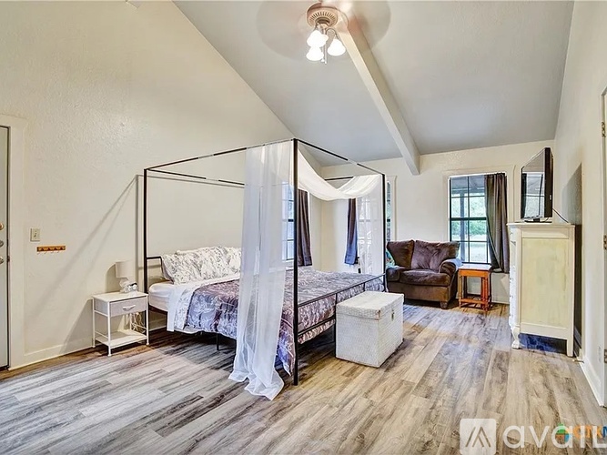 A bedroom with a canopy bed and a couch.