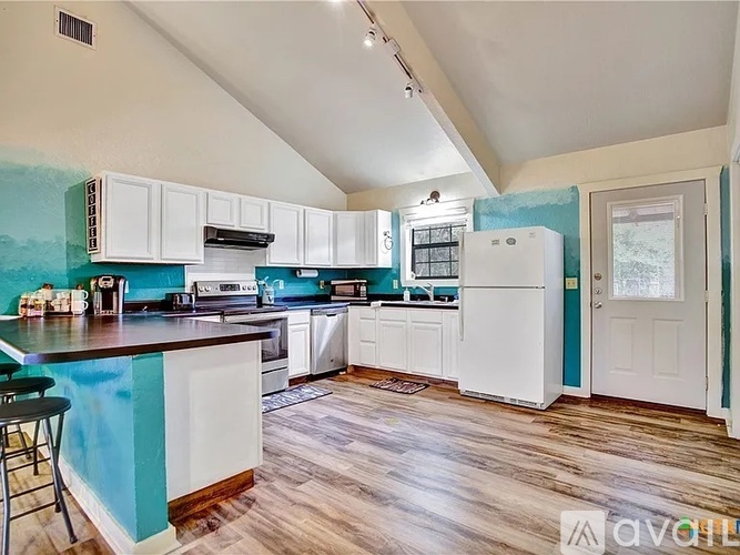 A kitchen with white cabinets and a blue painted accent wall.