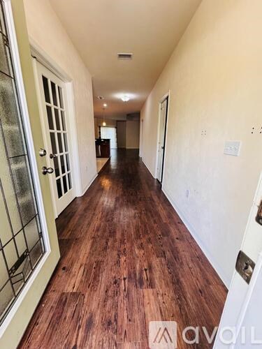 A long hallway with wood floors and white walls.