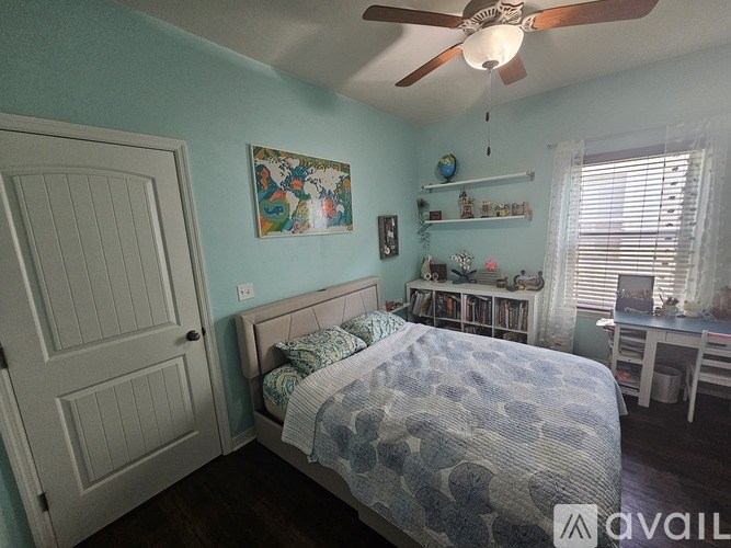 A bedroom with a bed, a ceiling fan, and a painting on the wall.
