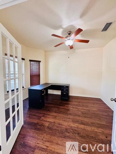 A room with a ceiling fan and a desk.