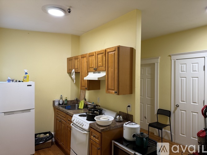 A kitchen with a white fridge, wooden cabinets, and a white stove top oven.