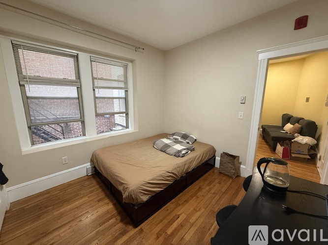 A bedroom with a bed, a window, and a wooden floor.