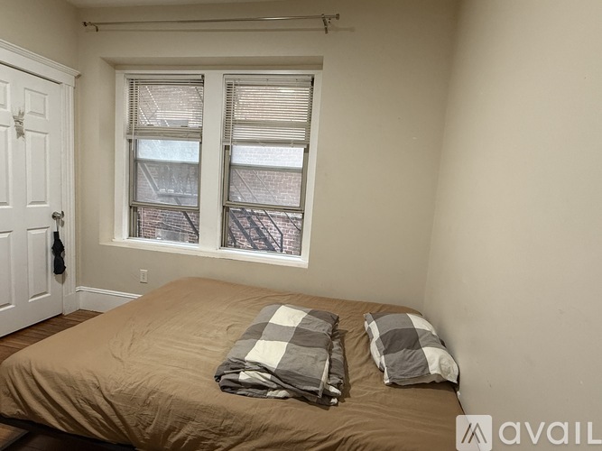 A bedroom with a bed, pillows, and a window with blinds.